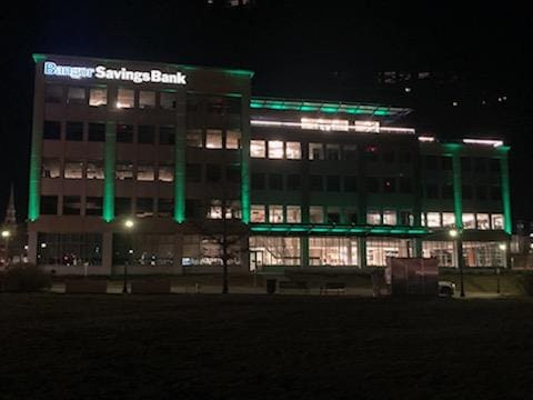 The building of Bangor Savings Bank lit up green. 