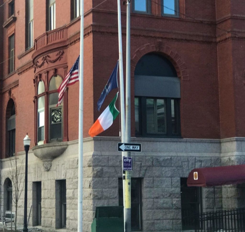 The American flag, Irish flag, and Maine state flag fly in front of Lewiston Maine's city hall. 