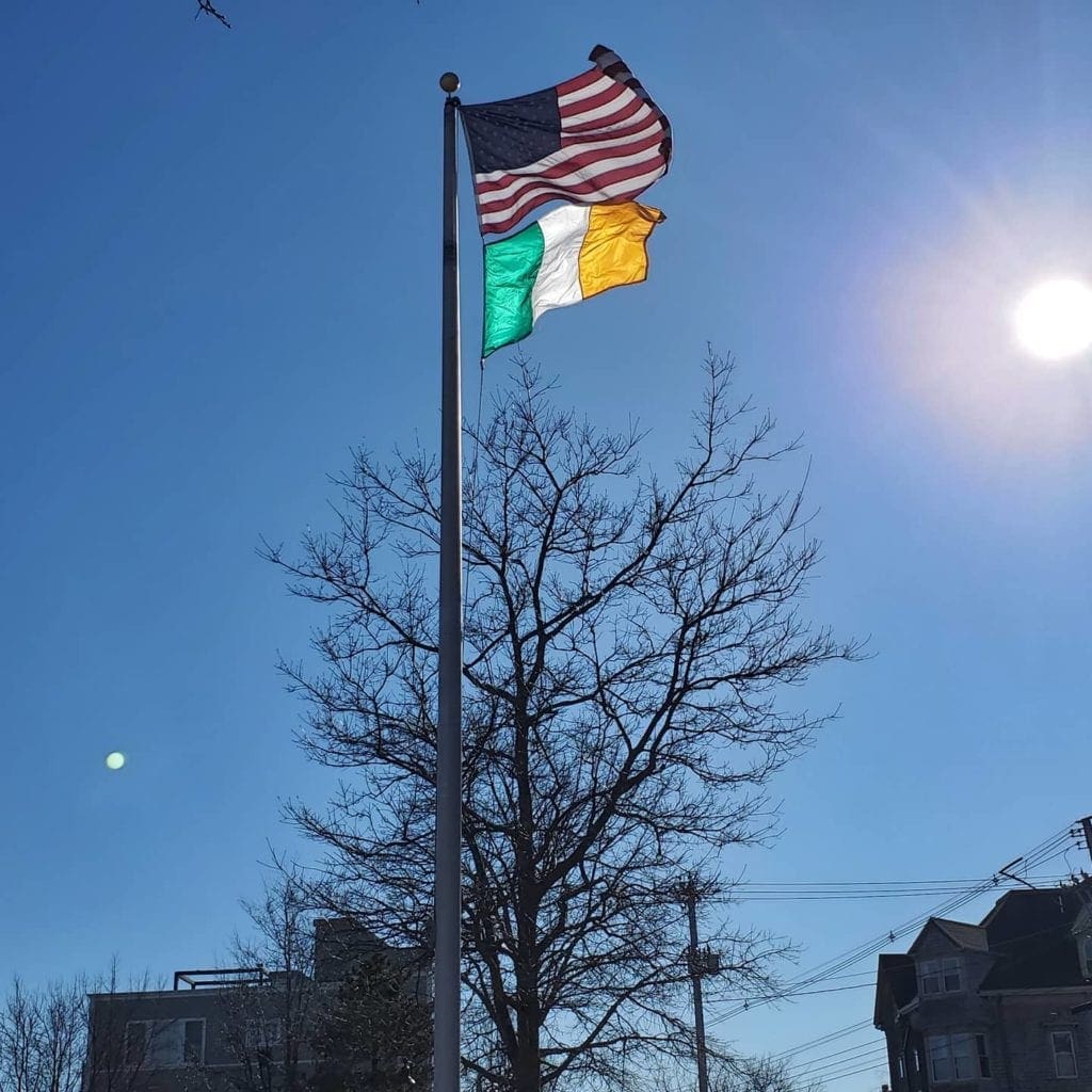 The American flag and the Irish flag fly together over Harbor View Park in Portland Maine. The sun is shining through the Irish flag brightening the colors. 